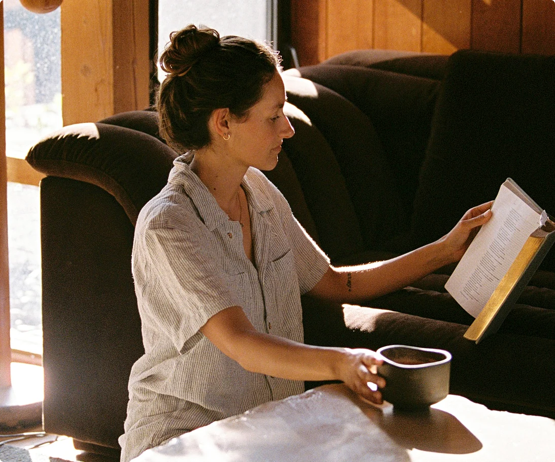 Person holding a warm ceramic bowl beside a sunlit window