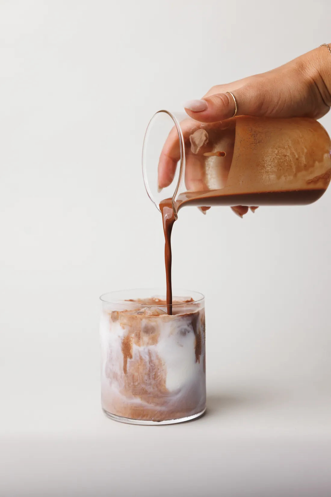 Ascend cacao poured over iced milk in a glass
